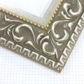 A large, reverse curve profile frame with an intricate leaf design bordered by a geometric outer edge and beaded inner lip.  A dark, matte Gold brown base with gold foil patina for added depth on the topmost points of the design. Strong, solid wood construction.

3.25 " witdth: ideal for large and oversize (extra large) images.